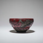Decorative glass bowl with red and black design on a gray background