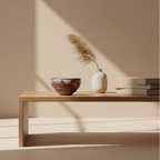 Minimalist interior with a wooden table holding a vase, bowl, and books against a beige wall.